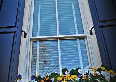 Outdoor shutters of Harmony Raised Panel Shutters with quarter top configuration.